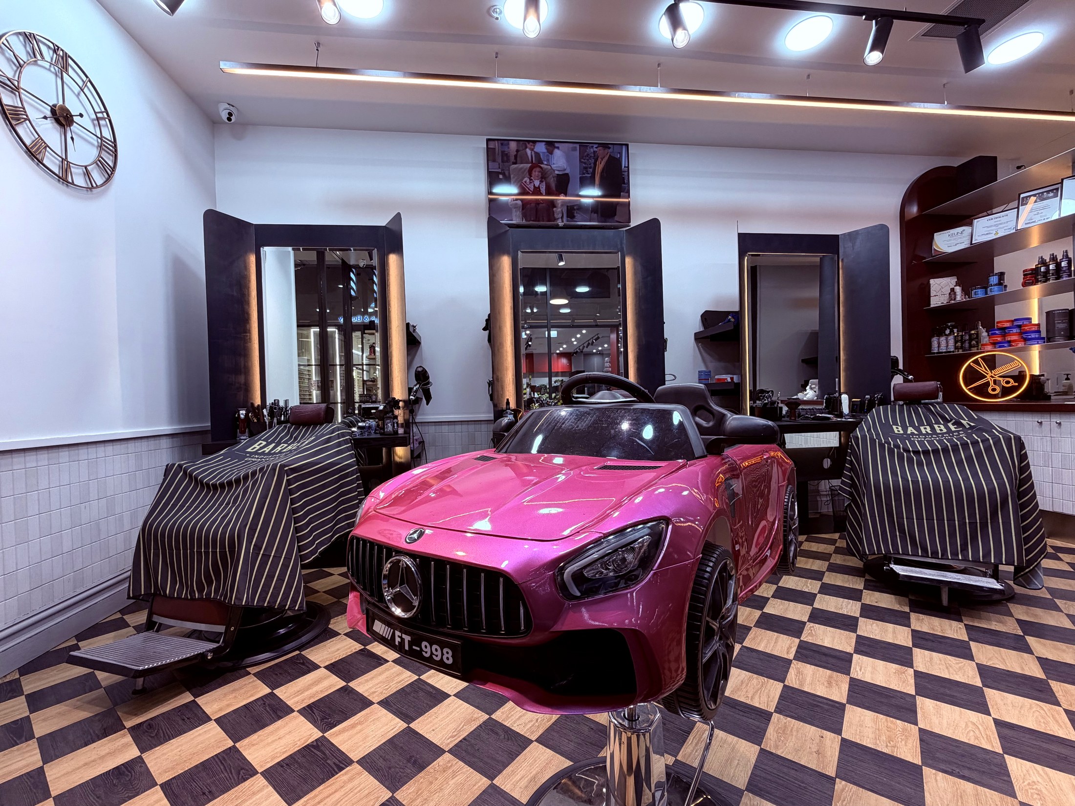 A pink toy car haircut seat for children inside the barbershop